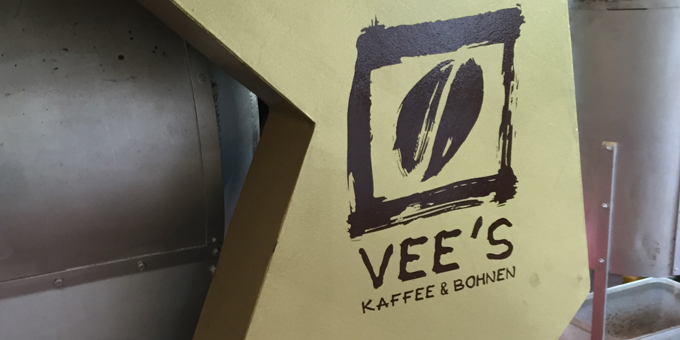 Das Logo der Vee Kaffee Rösterei auf goldenem Aufsteller