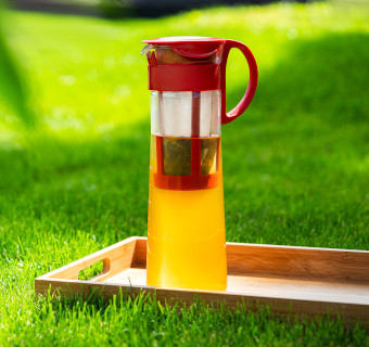 Eine Hario Cold Brew Karaffe steht auf einem Holzbrett auf dem Rasen